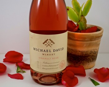 A bottle of Michael David Winery Insault Rosé 2018 with rose petals and a potted succulent plant.