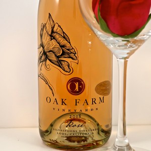 Bottle of Oak Farm Vineyards Rosé 2018 with a glass of wine and a rose flower.