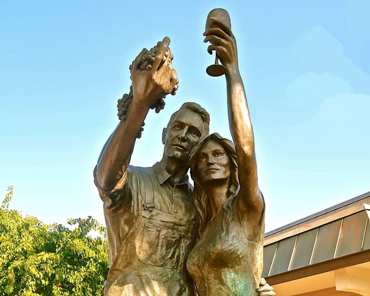 Bronze sculpture of a man and woman holding a wine glass, representing Lodi wine culture and community.