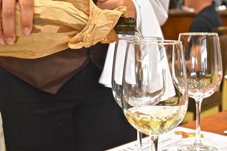 Person pouring wine into glasses at a wine tasting event, showcasing Lodi winegrapes.