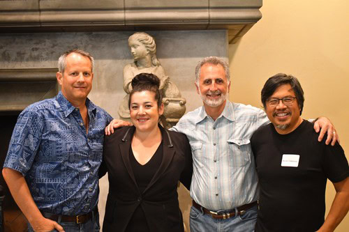 Group of four people smiling at a Lodi Winegrape Commission event, standing indoors with a sculpture in the background.