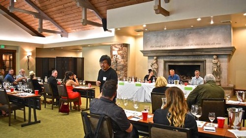 Attendees at a Lodi Winegrape Commission event in a spacious, well-lit conference room with a fireplace.