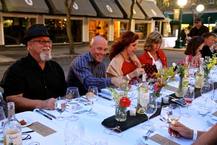 Group of people enjoying a dinner event outdoors with wine and flowers in Lodi, California.