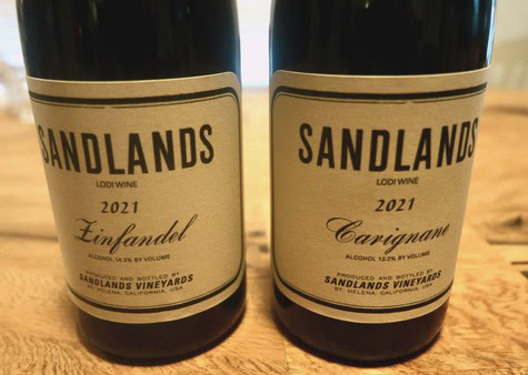 Two Sandlands wine bottles from Lodi Winegrape, 2021 vintage, on a wooden surface.