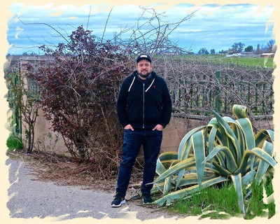 Man standing in a vineyard with large agave plants in Lodi, California, during daytime.
