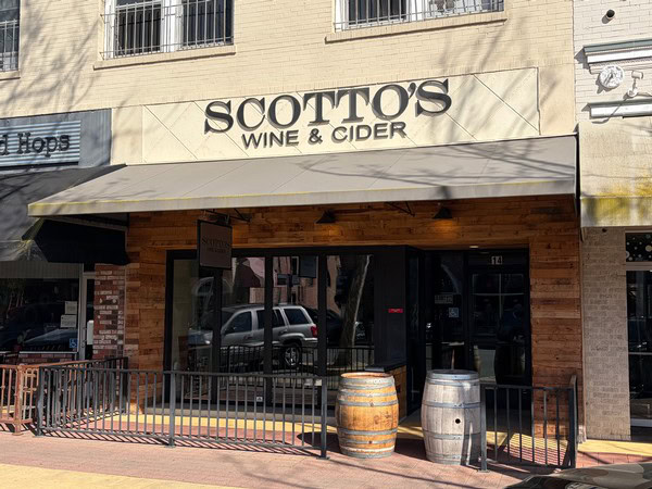 Exterior view of Scottos Wine & Cider shop with barrels and sidewalk seating in Lodi, California.