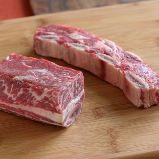 Raw beef short ribs on a wooden cutting board, ready for cooking or grilling.