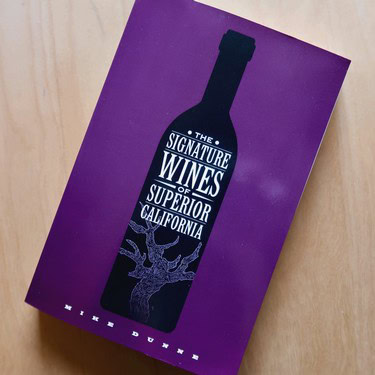 Brochure featuring a wine bottle silhouette with text about California wines on a purple background.