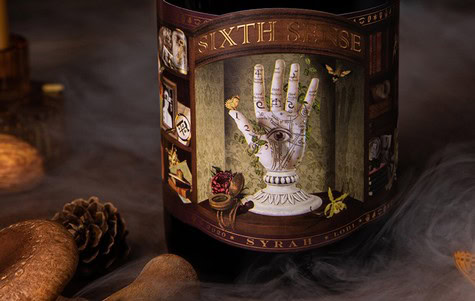 Close-up of Sixth Sense Syrah wine bottle with artistic label featuring a hand and eye design.