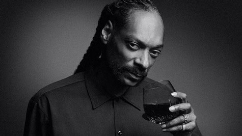 Close-up of a man holding a glass of red wine, focused on the wine and his expression.