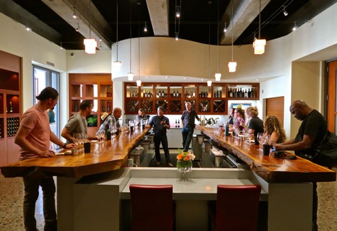 People enjoying wine tasting at a modern Lodi wine bar with a wooden counter and wine display shelves.