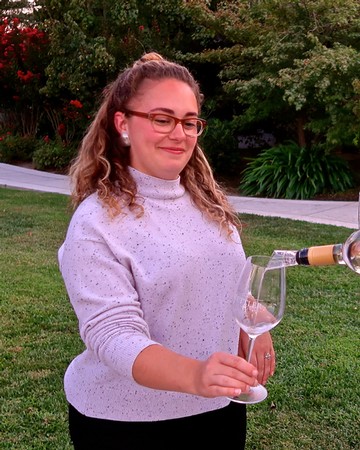 Woman pouring wine into a glass outdoors at a Lodi Winegrape Commission event.