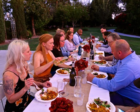 Group of people enjoying a dinner outdoors, celebrating with wine and food, at a Lodi Winegrape Commission event.