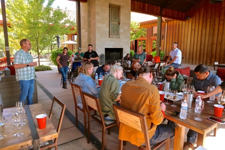 Group of people attending a wine tasting event at Lodi Winegrape Commission, seated around tables with wine bottles and glass.
