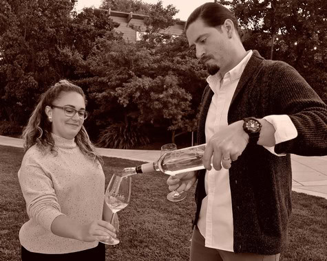 Man pouring wine into woman's glass during outdoor wine tasting event in Lodi, California.