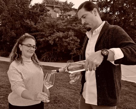 Man pouring wine into a glass for a woman during outdoor wine tasting event at Lodi Winegrape Commission.