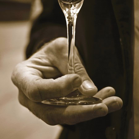 Close-up of a hand holding a wine glass, pouring wine, emphasizing wine tasting and wine industry in Lodi, California.