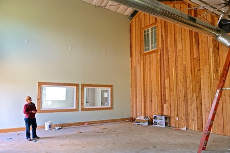 Construction worker inside a winery with wooden walls and large windows, preparing for wine production.