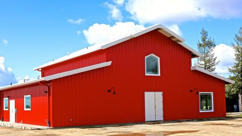 Red barn-style building with white doors and windows, under a blue sky with clouds, representing Lodi Winegrape Commission.