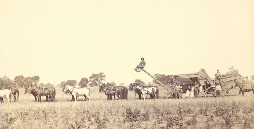 Vintage image of horses and early farming machinery in a field, representing agricultural history.