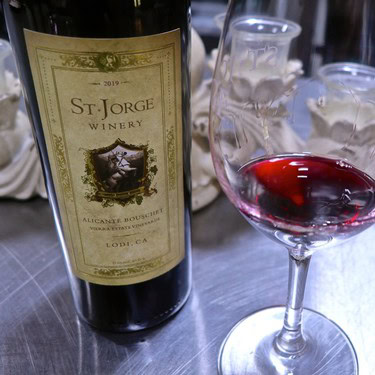 A bottle of St. Jorge Winery red wine with a glass of poured wine on a table.