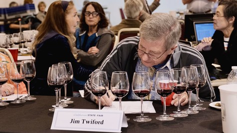 Man analyzing wine samples at Lodi Winegrape Commission event with multiple glasses of red wine.