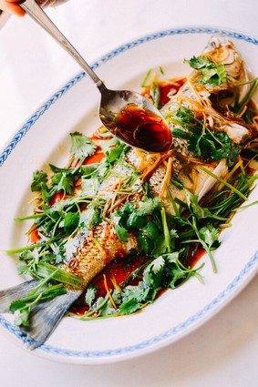Fresh fish garnished with herbs and served with a flavorful sauce on a white plate.