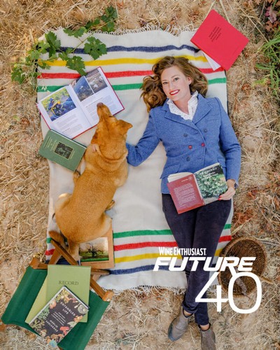Woman and dog reading outdoors on a blanket with wine books, representing Lodi Winegrape Commission's Future 40.
