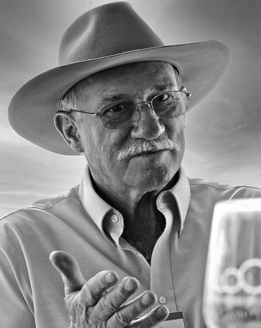 Senior man with glasses and hat at Lodi Winegrape Commission event, engaging with a smartphone.
