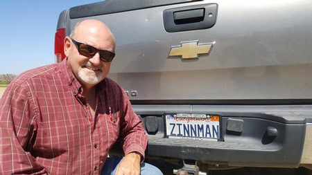 Man in sunglasses and red plaid shirt standing next to Chevrolet truck in Lodi wine region.