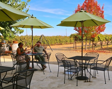 Outdoor vineyard patio with tables, chairs, and umbrellas at Lodi Winegrape Commission in California.