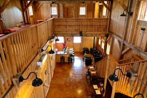 Interior view of a rustic wooden building with seating, kitchen area, and natural light, representing Lodi Winegrape region.