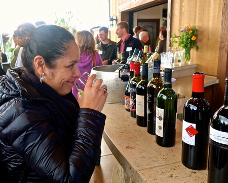 Woman enjoying wine tasting at Lodi Winegrape Commission event with bottles on display.
