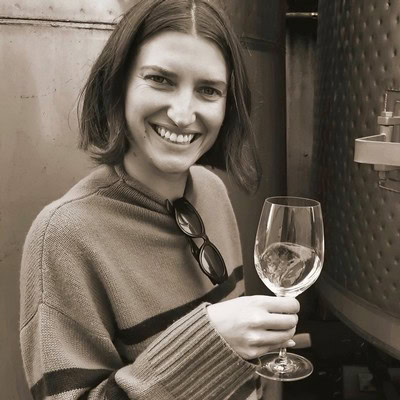 Smiling woman holding a glass of wine at Lodi Winegrape Commission event.