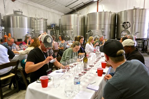 People tasting wine at a Lodi Winegrape Commission event in a winery setting.