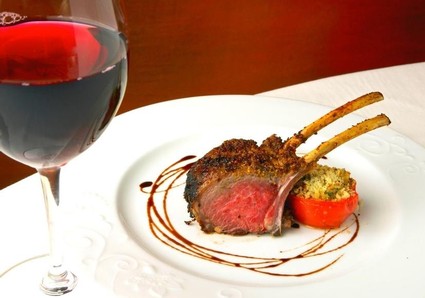 Gourmet lamb chop with tomato and wine glass, showcasing Lodi wine and local cuisine.