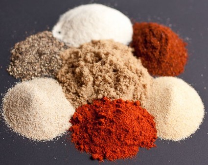 Variety of colorful ground spices arranged on a dark surface for culinary use.