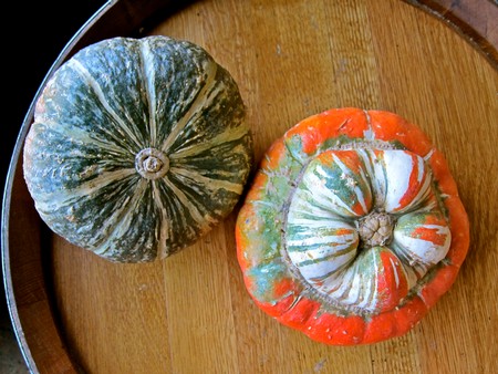Colorful decorative gourds on a wooden surface, used for fall decor and seasonal arrangements.