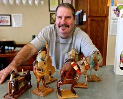 Man displaying handcrafted wooden horse sculptures at Lodi Winegrape Commission event.