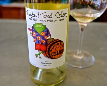 Lodi Winegrape Commission wine bottle with colorful label and glass of white wine.