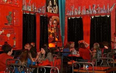 People dining in a vibrant restaurant with red walls and eclectic decor.