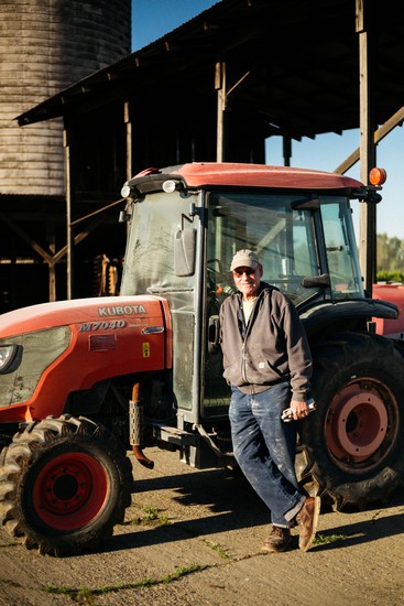 Person standing next to a Kubota tractor at a vineyard in Lodi, California.