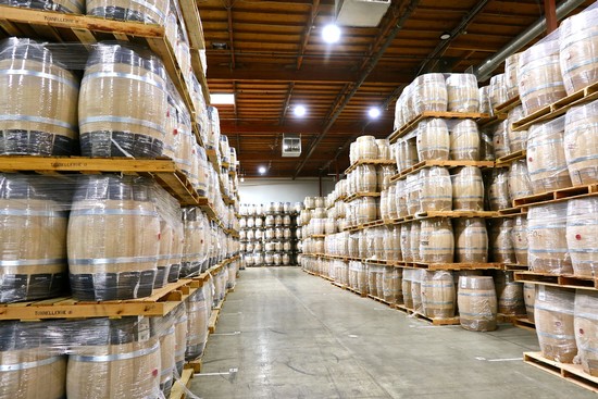 Wine barrels stored on wooden racks in a large warehouse for Lodi wine production.