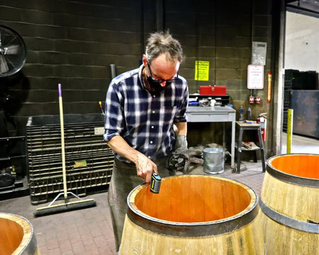 Winemaker inspecting wine barrels at Lodi Winegrape Commission facility in California.