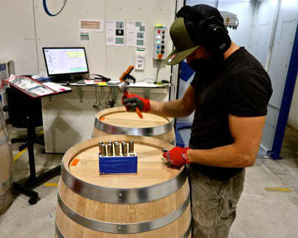Worker testing wine barrels at Lodi Winegrape Commission facility with specialized equipment and safety gear.