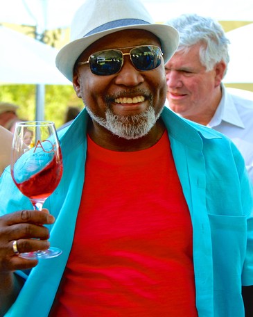 Smiling man with sunglasses holding a glass of red wine at a Lodi wine event.