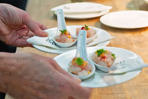 Chef serving gourmet appetizers on elegant white spoons at Lodi Winegrape event.