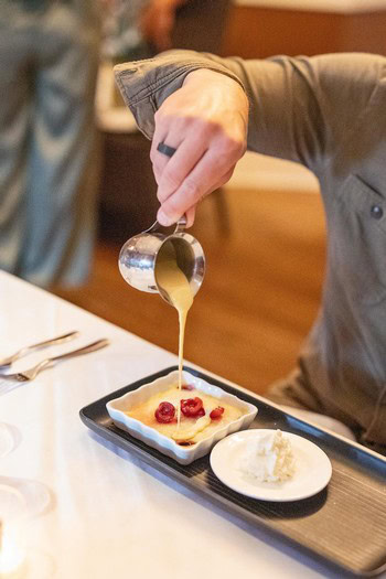 Pouring sauce over a dessert at Lodi Winegrape Commission event.