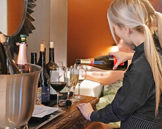 Woman pouring red wine into glass at Lodi Winegrape Commission event.