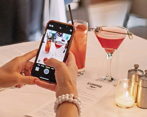 Person taking a photo of colorful cocktails on a table at a wine event.